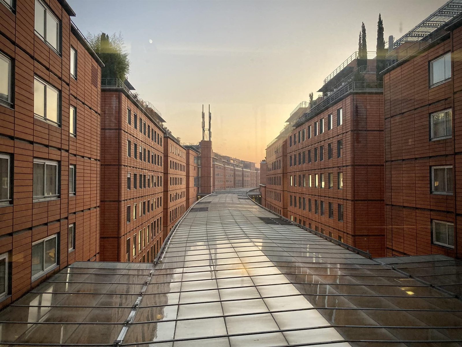 Immeubles de brique alignés de part et d'autre d'une verrière, au soleil couchant