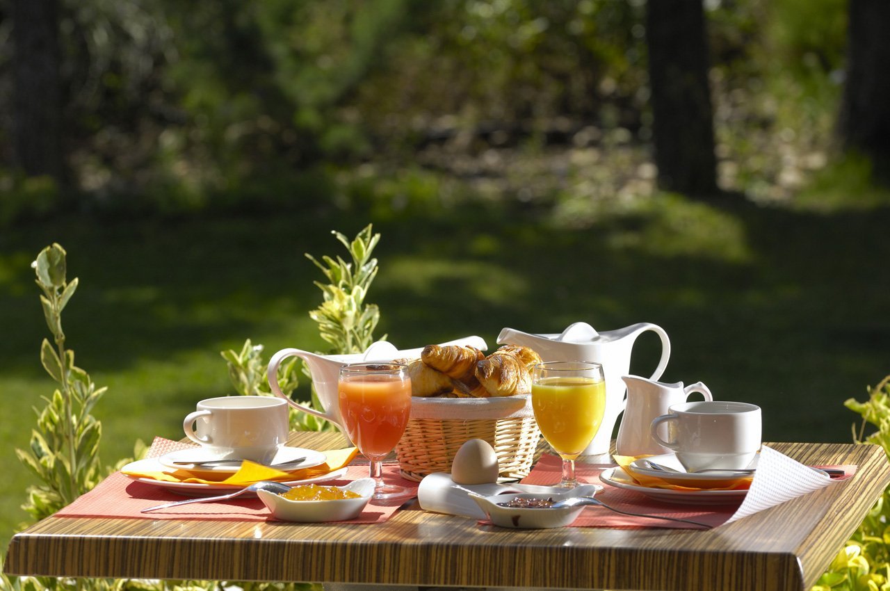 Petit-déjeuner servi sur une table de jardin, au soleil