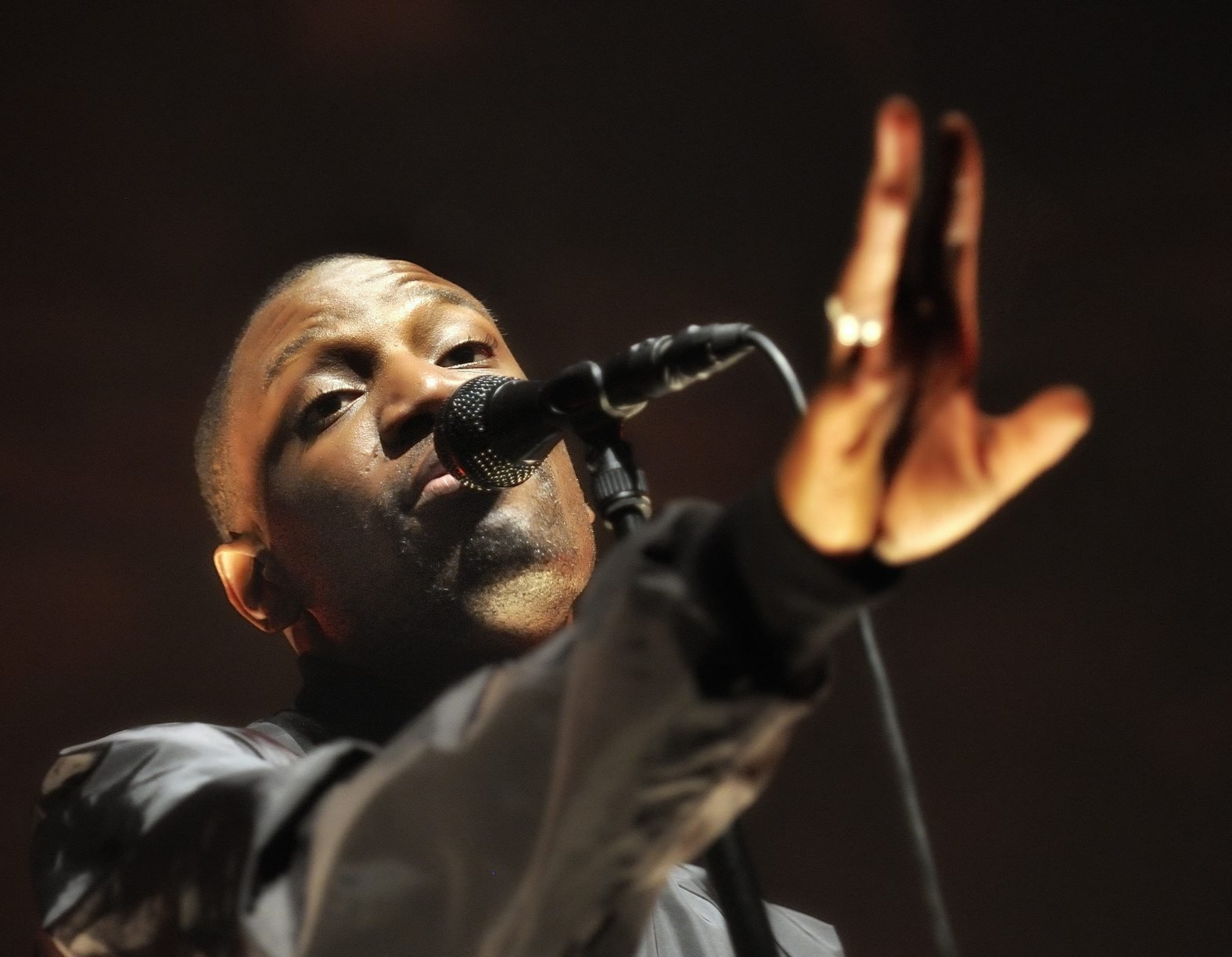 Chanteur au micro, la main tendue vers le public