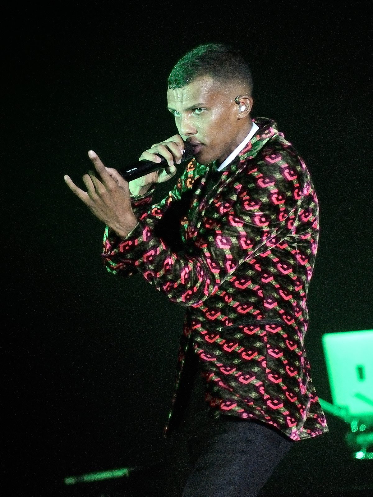 Chanteur en concert, micro en main, veste à motifs colorés
