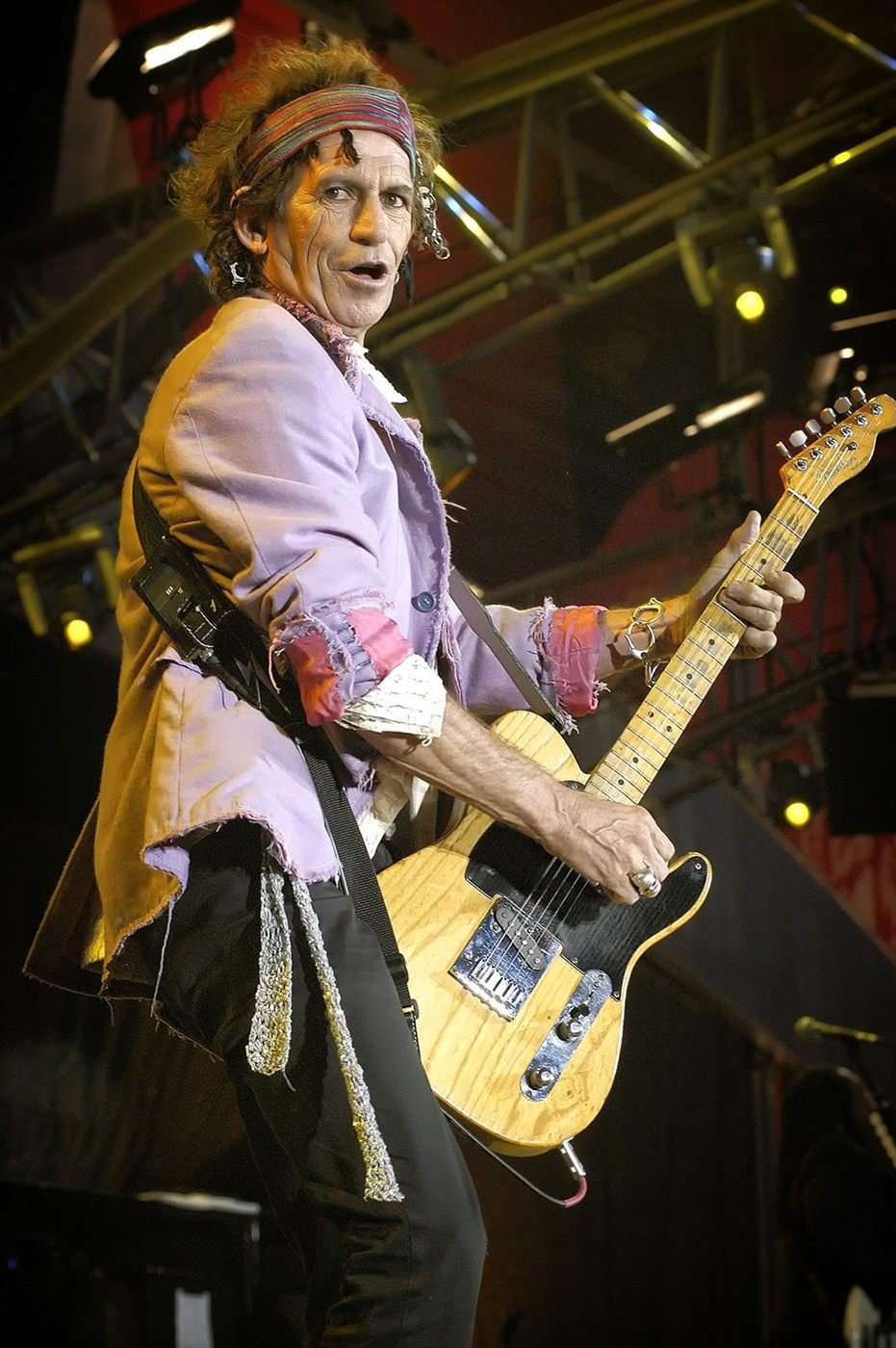 Guitariste en veste claire jouant sous les projecteurs