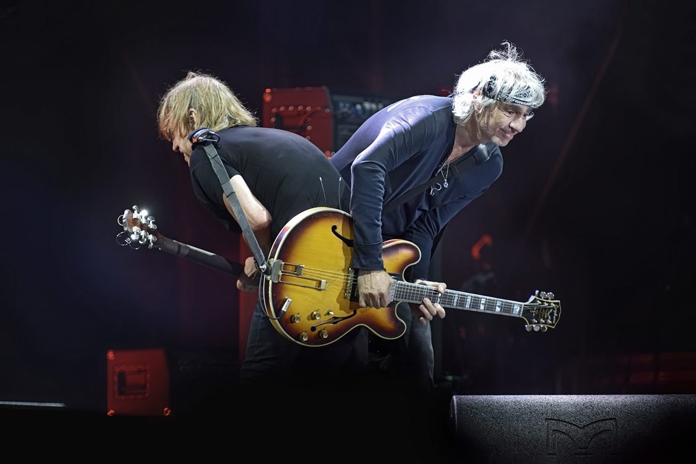 Deux guitaristes sur scène, penchés sur leurs instruments