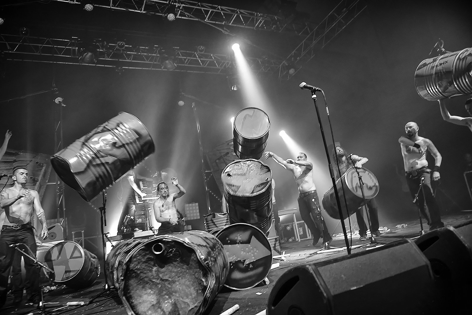 Les Tambours du Bronx en concert : percussionnistes frappant des fûts métalliques sous les projecteurs, en noir et blanc